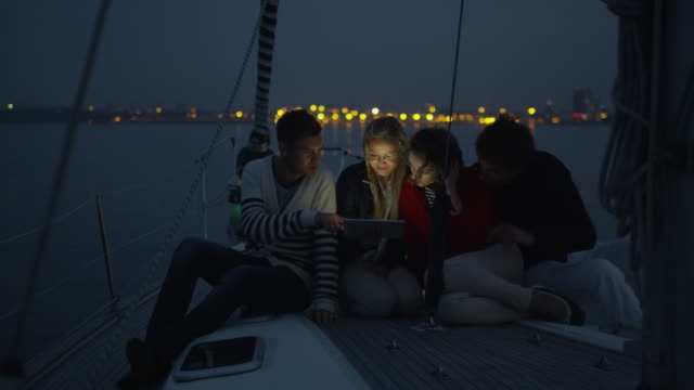 Gruppe-von-Menschen-nutzen-Tablet-auf-einer-Yacht-im-Meer-in-der-Nacht.