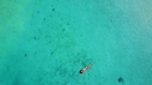 Aerial-view-of-an-attractive-woman-in-a-bikini-floating-in-crystal-clear-sea.-Pretty-beatiful-girl-swimming-in-Indian-ocean