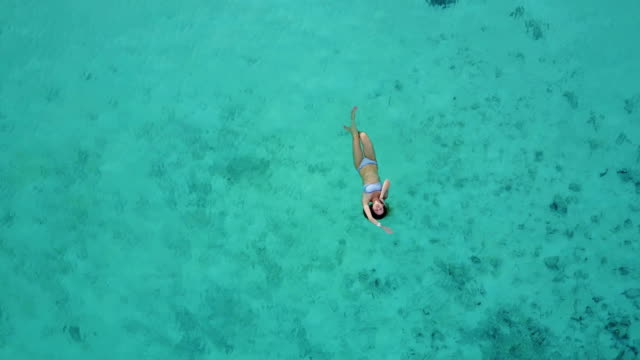 Vista-aérea-de-una-atractiva-mujer-en-un-bikini-flotando-en-el-mar-de-aguas-cristalina.-Bonita-hermosa-chica-nadando-en-el-Océano-Índico