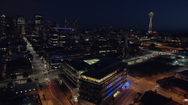 Aerial-of-Downtown-Seattle-Lit-at-Night-with-Cars-Driving-on-City-Streets