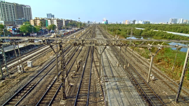 Time-lapse-shot-of-the-moving-suburban-(local)-trains,-on-the-one-side-there's-protected-mangrove-forest-(wetland)-and-all-other-sides-are-covered-with-city-buildings,-Mumbai,-India