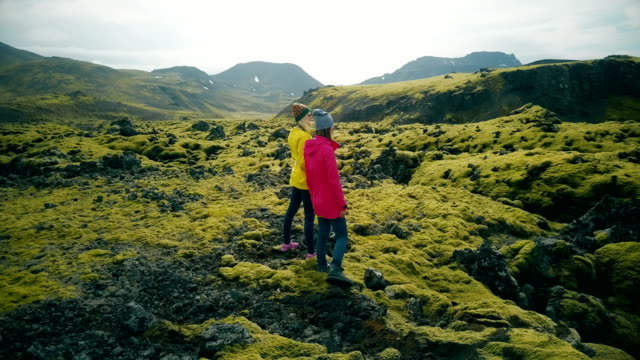 Aerial-view-of-two-woman-walking-on-the-lava-fields-in-Iceland.-Tourists-enjoying-the-landscape,-exploring-the-territory