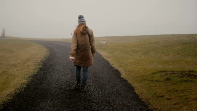 Vista-trasera-del-joven,-paseando-por-el-campo-solo.-Elegante-mujer-explorando-la-naturaleza-de-Islandia