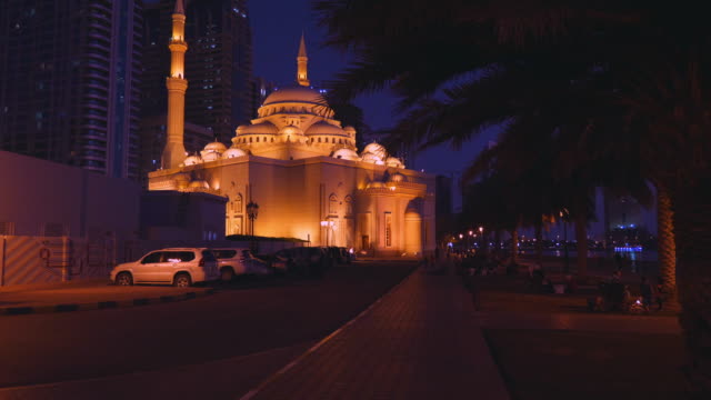 Move-the-camera-to-a-beautifully-lit-mosque-at-night-along-the-alley.