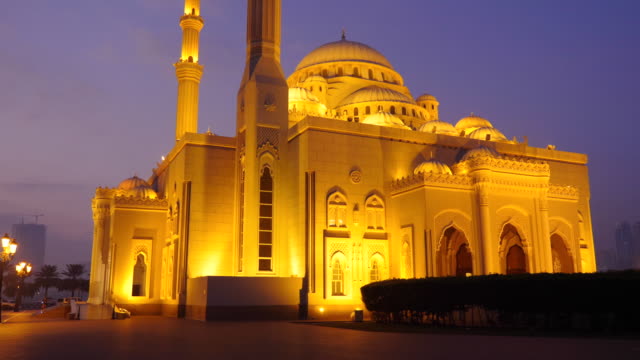 Wandern-Sie-entlang-der-arabischen-Moschee-in-der-Nacht.-Ein-einsamer-Radfahrer-fährt-durch-die-Park-Gasse.-Beleuchtete-goldene-Lichter-Moschee.