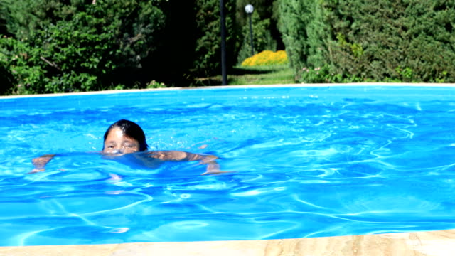 Kleiner-Junge-im-Schwimmbad-lächelnd-mit-einer-Kamera