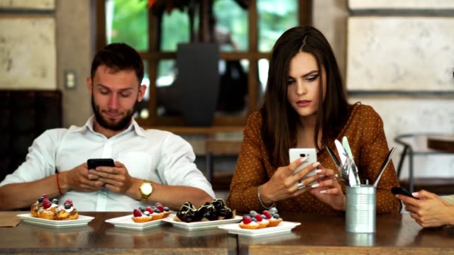 Multi-ethnischen-Gruppe-von-Freunden-in-einem-Restaurant-sitzen-und-mit-Blick-auf-jede-Langeweile-in-Ihrem-Telefon