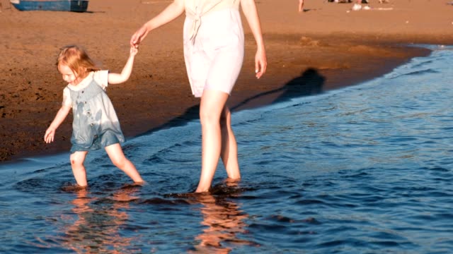 Mamá-y-niña-jugando-en-la-playa-del-río-en-la-puesta-de-sol-y-nadar.