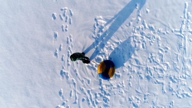 Jungen-von-7-Jahren-ist-mit-dem-Schlauch-im-Schnee-Wirbeln.-Luftaufnahmen.