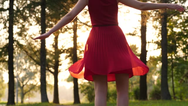 Glücklich-lächelnde-Frau-im-roten-Kleid-mit-transparenten-Rock-tanzen-und-umdrehen