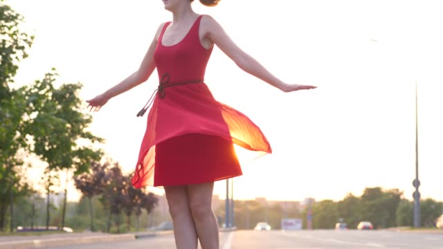 Glückliche-Frau-im-roten-Kleid-tanzen-und-drehen-um-auf-Straße