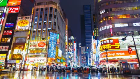 Shinjuku-Bezirk-in-der-regnerischen-Nacht-mit-Publikum-vorbeigehen-Zebrastreifen.-Tokio,-Japan.-4K-Zeitraffer.