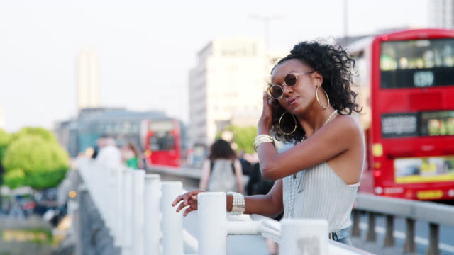 Modisch-junge-schwarze-Frau-stützte-sich-auf-das-Geländer-einer-Brücke-in-der-Stadt-umzusehen,-Seitenansicht