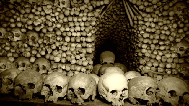 4K-footage-of-Human's-bones-and-skulls-in-the-underground-catacombs-with-old-chronicle-film-effect-after-processing.