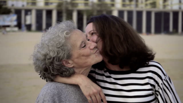 Smiling-mature-daughter-kissing-and-embracing-senior-mother.