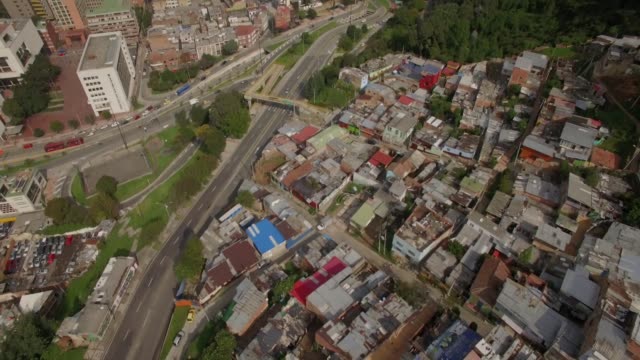Aerial-tilting-up-from-shanty-town-to-downtown-office-buildings-in-Bogota,-Colombia