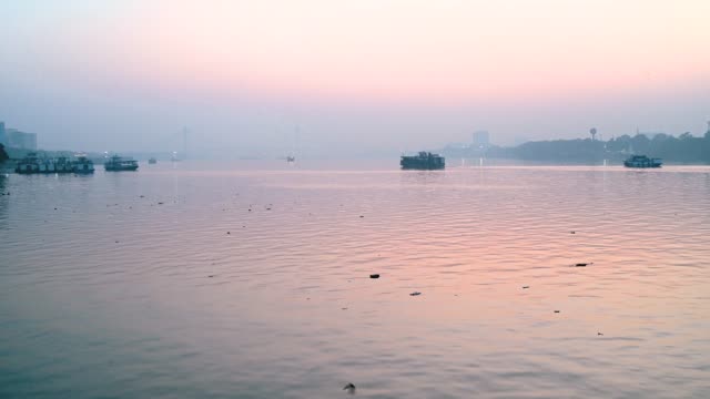 Boot-bewegt-sich-über-Ganges-Fluss-in-Kolkata-Stadt-zur-Zeit-von-Sonnenuntergang-in-der-Nähe-von-Vidyasagar-setu-oder-zweite-Hooghly-Bridge-in-Westbengalen,-Indien.