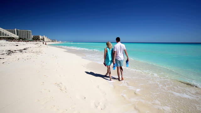 Young-couple-with-slippers-walking--along-the--beach