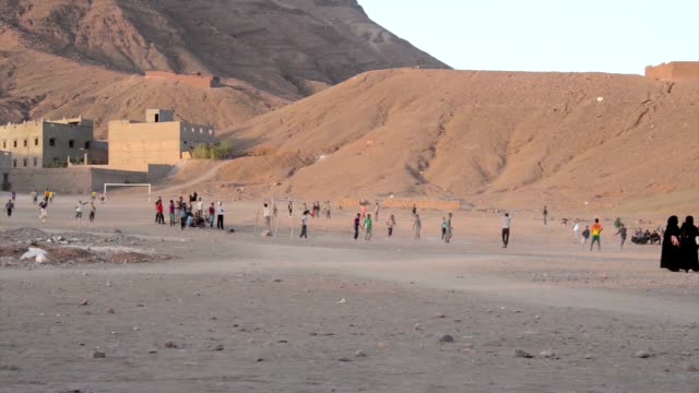 Boys-and-men-playing-soccer-in-the-evening-on-a-sand-field-in-Tamegroute