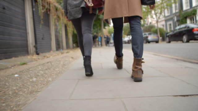 Close-Up-Of-Couple's-Feet-Walking-Along-City-Street