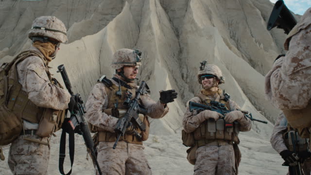 Gruppe-von-Soldaten-steht-in-einem-Kreis-und-hört-Aufträge-von-Commander-während-Briefing-vor-der-militärischen-Operation-in-der-Wüste.