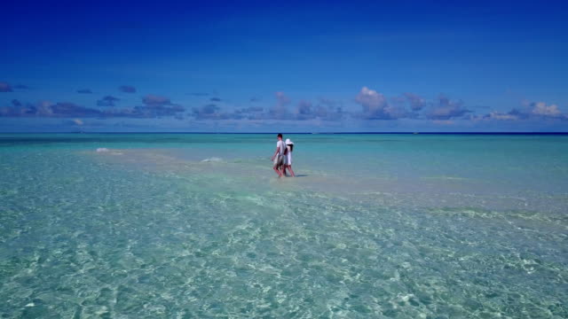 v03913-Aerial-flying-drone-view-of-Maldives-white-sandy-beach-2-people-young-couple-man-woman-romantic-love-on-sunny-tropical-paradise-island-with-aqua-blue-sky-sea-water-ocean-4k
