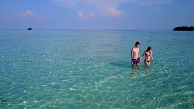 v03993-fliegenden-Drohne-Luftaufnahme-der-Malediven-weißen-Sandstrand-2-Personen-junges-Paar-Mann-Frau-romantische-Liebe-auf-sonnigen-tropischen-Inselparadies-mit-Aqua-blau-Himmel-Meer-Wasser-Ozean-4k