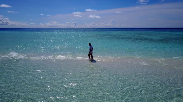v03909-Aerial-flying-drone-view-of-Maldives-white-sandy-beach-2-people-young-couple-man-woman-romantic-love-on-sunny-tropical-paradise-island-with-aqua-blue-sky-sea-water-ocean-4k