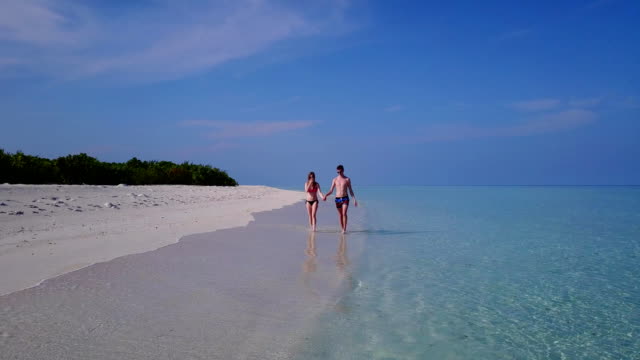 v03996-fliegenden-Drohne-Luftaufnahme-der-Malediven-weißen-Sandstrand-2-Personen-junges-Paar-Mann-Frau-romantische-Liebe-auf-sonnigen-tropischen-Inselparadies-mit-Aqua-blau-Himmel-Meer-Wasser-Ozean-4k
