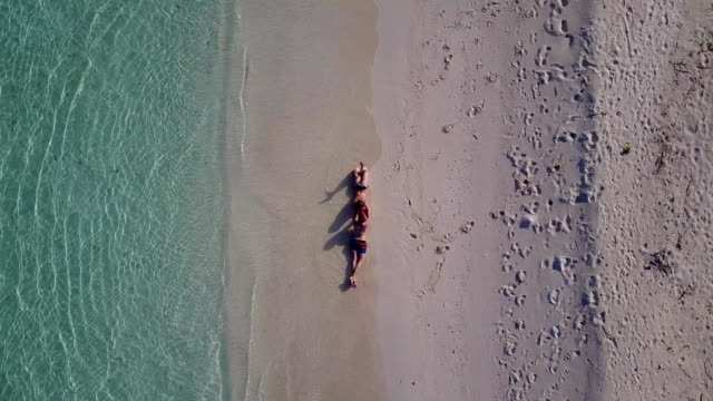 v03880-Aerial-flying-drone-view-of-Maldives-white-sandy-beach-2-people-young-couple-man-woman-romantic-love-on-sunny-tropical-paradise-island-with-aqua-blue-sky-sea-water-ocean-4k