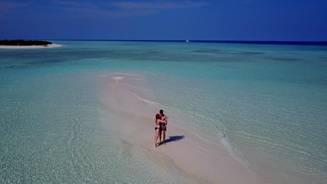 v03863-Aerial-flying-drone-view-of-Maldives-white-sandy-beach-2-people-young-couple-man-woman-romantic-love-on-sunny-tropical-paradise-island-with-aqua-blue-sky-sea-water-ocean-4k