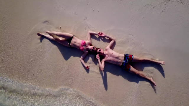 v03869-fliegenden-Drohne-Luftaufnahme-der-Malediven-weißen-Sandstrand-2-Personen-junges-Paar-Mann-Frau-romantische-Liebe-auf-sonnigen-tropischen-Inselparadies-mit-Aqua-blau-Himmel-Meer-Wasser-Ozean-4k
