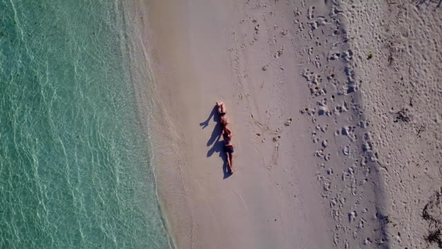 v03902-fliegenden-Drohne-Luftaufnahme-der-Malediven-weißen-Sandstrand-2-Personen-junges-Paar-Mann-Frau-romantische-Liebe-auf-sonnigen-tropischen-Inselparadies-mit-Aqua-blau-Himmel-Meer-Wasser-Ozean-4k