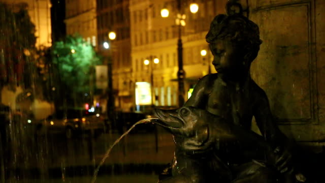 Statue-der-Junge-sitzt-am-Brunnen-halten-Fische-in-der-Nacht,-Romantik
