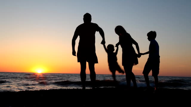 Familie-Silhouette-bei-Sonnenuntergang-in-der-Nähe-von-dem-Meer-Mutter-Vater-Kinder