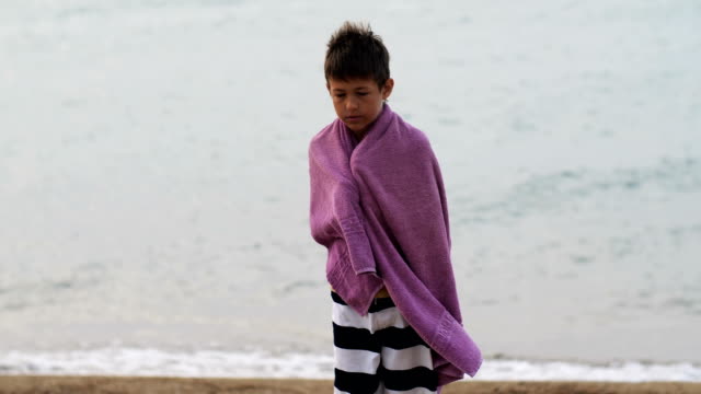 niño-refugiado-triste-cansado-en-una-toalla-encuentra-sola-mirando-a-la-cámara,-Chico-está-tratando-de-mantener-el-calor