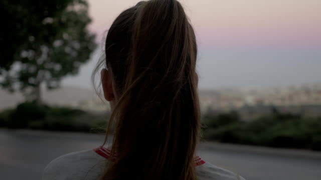 Long-hair-girl-on-the-roadside-with-the-car-traffic-turns-her-back-to-the-camera.