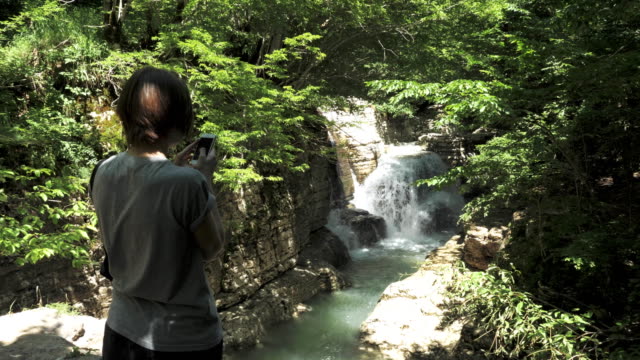 Junges-Mädchen-nimmt-Foto-des-kleinen-Wasserfalls,-Georgien
