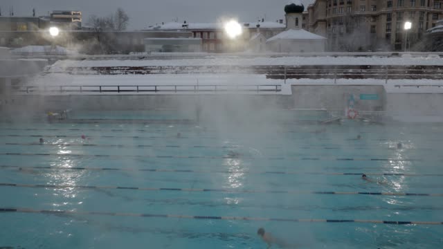 Vapor-se-levanta-lentamente-sobre-una-piscina-abierta-en-invierno
