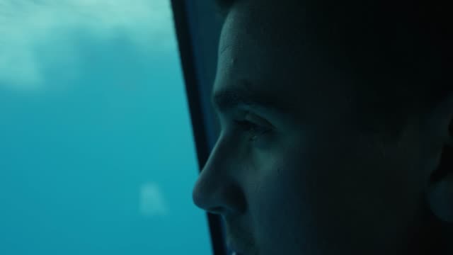 Close-up-on-a-Man-Looking-at-the-Underwater-Life-while-Being-on-the-Boat-with-the-Glass-Bottom.