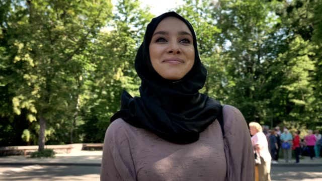 Young-happy-muslim-girl-in-hijab-is-smiling-and-going-to-university-in-daytime-in-summer,-religious-concept,-studying-concept