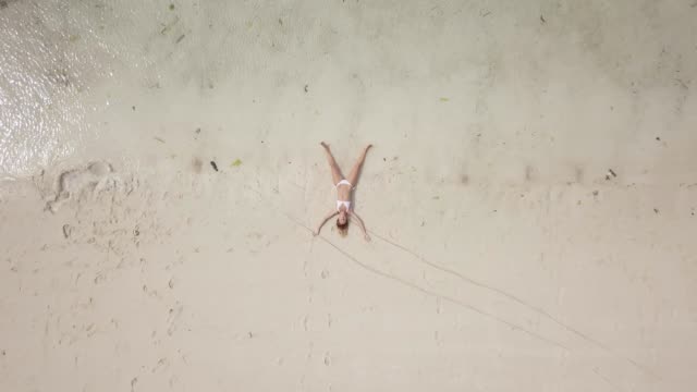 Mujer-joven-flotando-en-el-agua-como-forma-de-estrella-en-aguas-poco-profundas,-vacaciones-viajes-exotismo.-Rodada-en-4K-con-drone,-vista-aérea