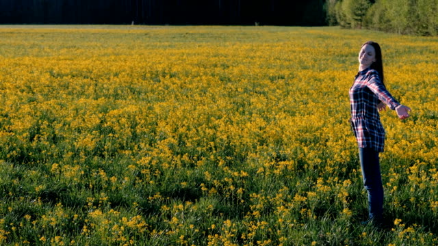 Morena-mujer-camina-en-el-campo-de-flores-amarillas.-Se-estira-y-respira-profundamente.