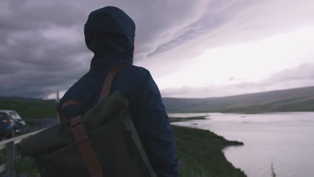 Mann-mit-einem-Rucksack-Aussicht-auf-Stromy-Wolken-über-dem-See,-filmische-erschossen