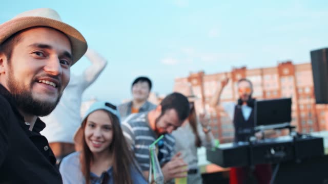 Gruppe-von-fröhlichen-Jugendlichen-Selfie-mit-Kamera-oder-Smartphone-am-Sommerfest-auf-dem-Dach