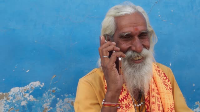 Closeup-de-un-hombre-Santo-hindú-muy-contento-de-comunicar-un-teléfono-de-pantalla-táctil