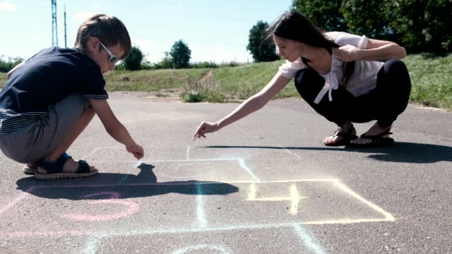 Mother-and-son-drawing-together-hopscotch-on-the-asphalt.