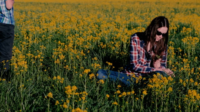 Boy-gives-his-mother-a-bouquet-of-wild-flowers-and-kisses-her-sitting-on-the-grass-among-the-yellow-flowers.
