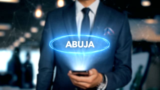 Businessman-With-Mobile-Phone-Opens-Hologram-HUD-Interface-and-Touches-Word-Country---Capital---ABUJA