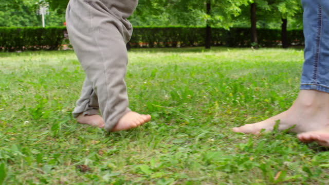 Madre-enseñanza-bebé-descalzo-a-caminar-en-el-Parque
